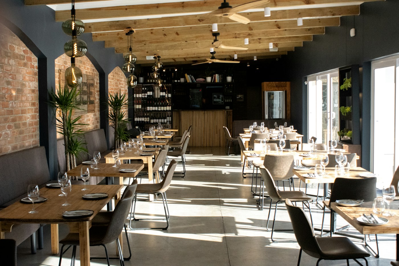 Interior de un restaurante con mesas de madera y pared de ladrillo.